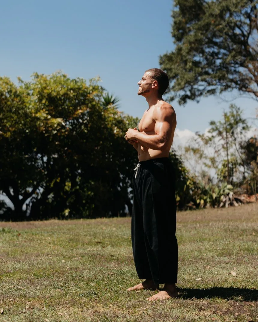 Omar standing barefoot on grass in the sun, looking upward