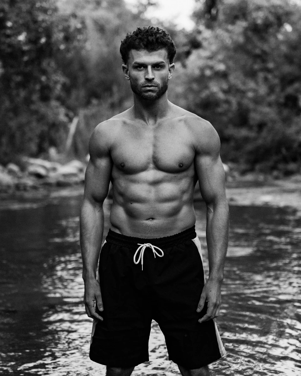 Omar Thali standing in a river, black-and-white portrait