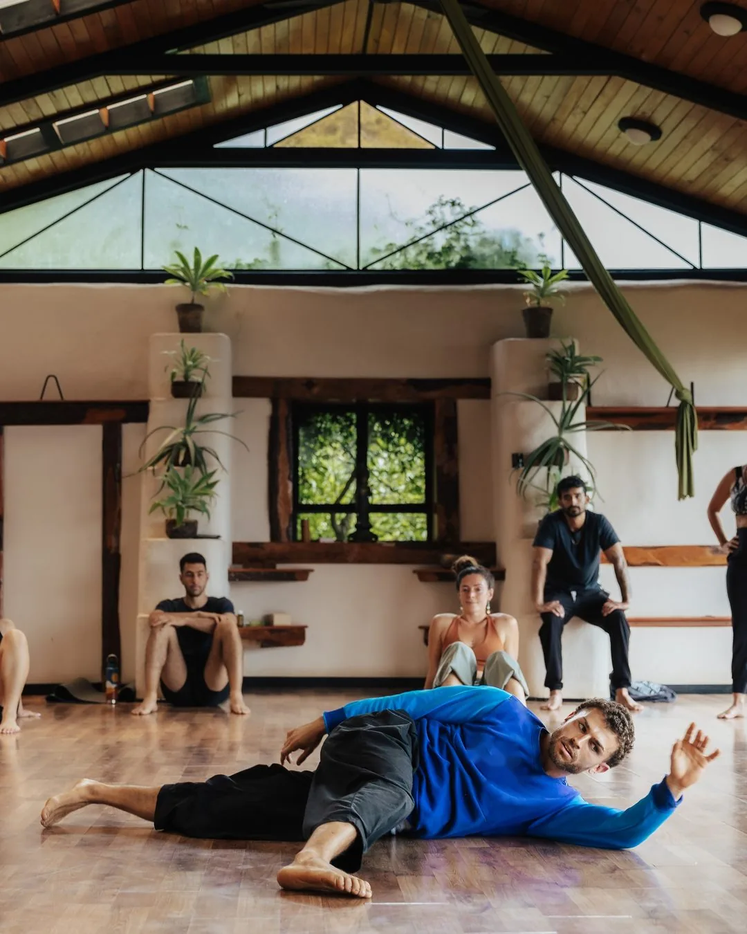 Omar Thali guiding a somatic movement class on the floor while students observe